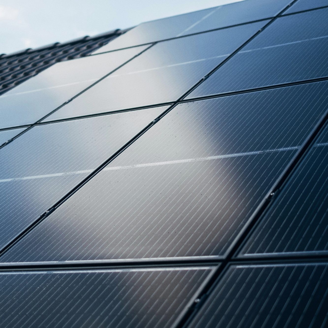 Dunkle Solarpanels auf einem Dach, reflektieren das Licht des Himmels.